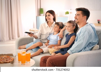 Happy family watching TV on sofa at home