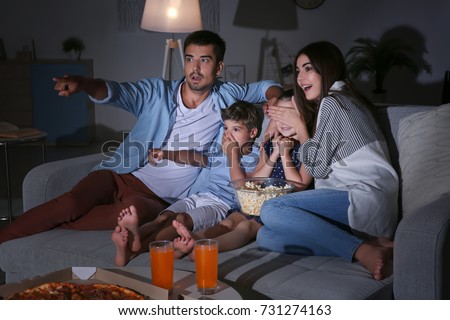 Happy family watching TV on sofa at night