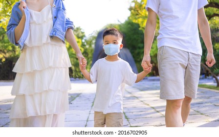 Happy Family Wearing The Medical Mask And Walking In The Park.