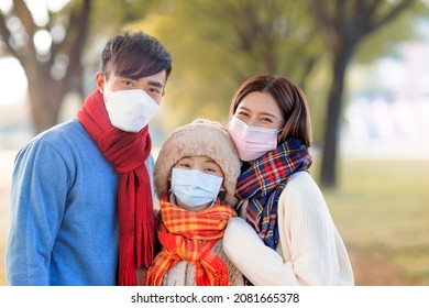 Happy Family Wearing Medical Mask And Walking In The Fall Park