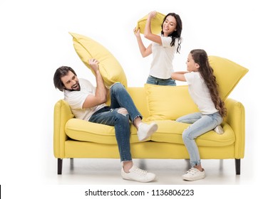 Happy Family In White Shirts On Yellow Sofa Having Pillow Fight Isolated On White