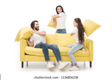 Happy Family In White Shirts On Yellow Sofa Having Pillow Fight Isolated On White