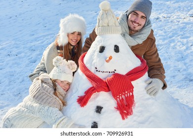 Happy Family In Winter Building Snowman In The Park