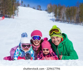  Happy Family In Winter Clothes Lie On The Snow At Ski Resort