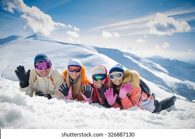 Happy Family In Winter Clothes Lie On The Snow At Ski Resort