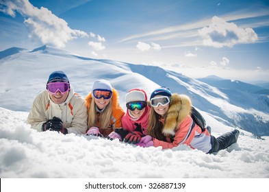 Happy Family In Winter Clothes Lie On The Snow At Ski Resort