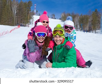 Happy Family In Winter Clothes Lie On The Snow At Ski Resort