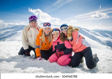 Happy Family In Winter Clothes Lie On The Snow At Ski Resort