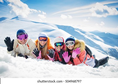 Happy Family In Winter Clothes Lie On The Snow At Ski Resort