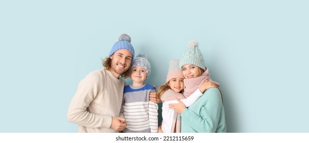 Happy family in winter clothes on light blue background - Powered by Shutterstock