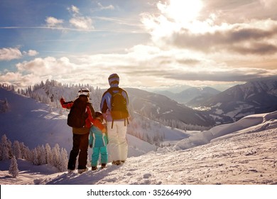 Happy Family In Winter Clothing At The Ski Resort, Winter Time, Watching At Mountains In Front Of Them