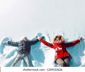 Happy Family In Winter! Mother With Son Child Lying On Snow Having Fun, Making Snow Angels, In Positive, Blank Copy Space Background, Top View