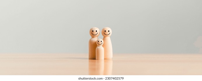 Happy family in wooden figure on table background. Family with one child and parents caring their son or daughter. Love and relationship concept.