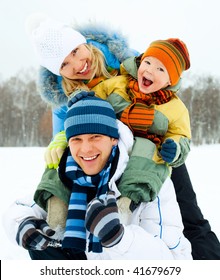 Happy Family, Young Couple And Their Son Spending Time Outdoor In Winter