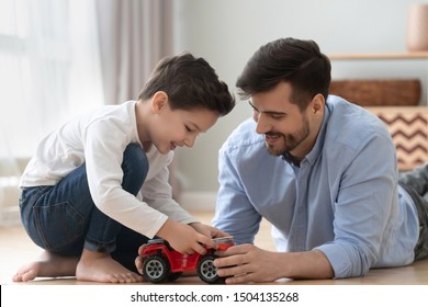 Happy Family Young Dad And Cute Little Son Play Toy Car On Warm Heated Floor At Home, Small Preschool Child Boy Having Fun Bonding With Father Teach Kid Learn Automobile Enjoy Leisure Lifestyle Game