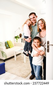 glückliche Familie mit kleinen Kindern, die Gäste an ihrer Haustür weit offen begrüßen.