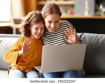 Happy family young loving mother and cute little girl daughter looking at computer screen, smiling and waving while having video call with family on laptop, relaxing together on sofa at home - Powered by Shutterstock