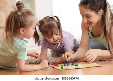 Happy Family. Young Mother Playing Ludo Boardgame With Her Children Daughters While Spending Time Together At Home.