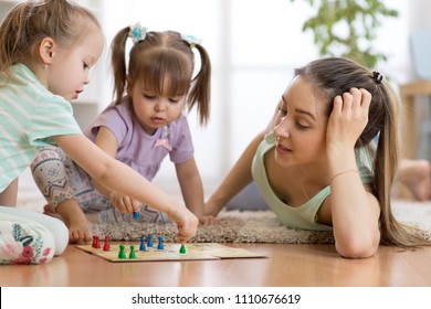 Happy Family. Young Mother Playing Ludo Boardgame With Her Children Daughters While Spending Time Together At Home.