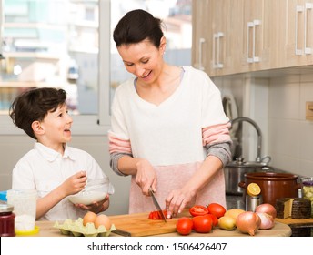 Happy Family Of Young Mother And Preteen Son Cooking Together At Home

