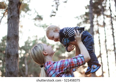 A happy family. Young mother throwing baby in nebe. Portret mother for mother and little son in the park. - Shutterstock ID 521458375
