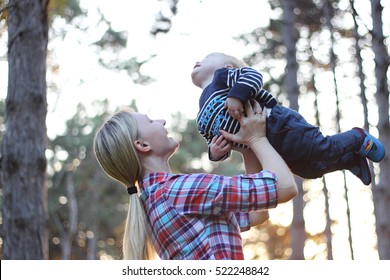 A happy family. Young mother throwing baby in nebe. Portret mother for mother and little son in the park. - Shutterstock ID 522248842