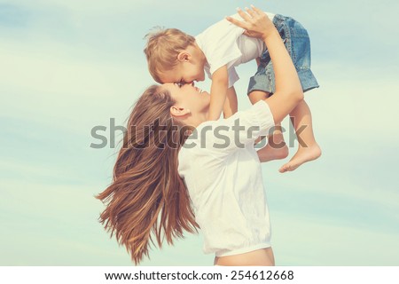 Happy family. Young mother throws up baby in the sky, on sunny day. Portrait mom and little son on the beach. Positive human emotions, feelings, joy.