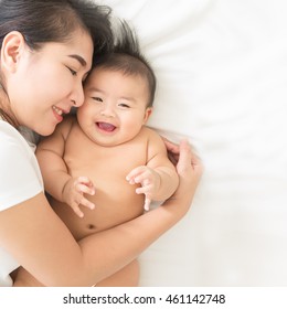 Happy Family.asian  Mother Playing With Her Baby In The Bedroom.