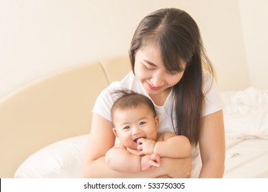 Happy Family.asian  Mother Playing With Her Baby In The Bedroom.