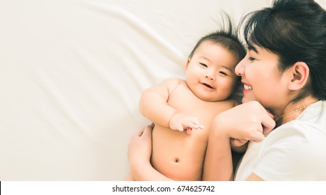 Happy Family.asian Mother Playing With Her Baby In The Bedroom.