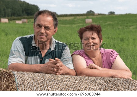 Happy farmer couple after hay harvesting.