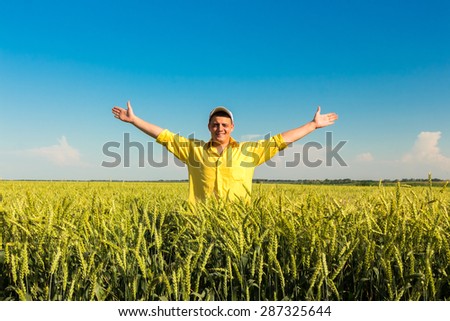 Happy farmer in field with handsup to a blue sky.