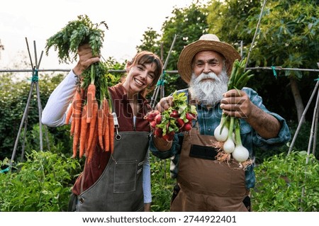 Happy farmers smiling at the camera while proudly holding a vibrant bunch of freshly harvested organic vegetables in a picturesque bio farm setting
