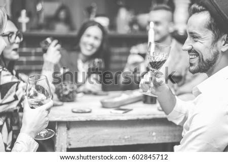 Happy fashion friends toasting wine in trendy cocktail bar restaurant - Young people having fun drinking and laughing together - Focus on right man mouth eye - Black and white editing - Warm filter