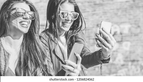 Happy fashion friends watching videos on smartphone - Girlfriends having fun with social technology trend - Youth lifestyle and millennials generation - Black and white editing - Focus left girl face 