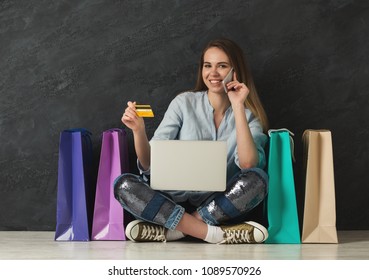 Happy fashion woman buying online with laptop and credit card, with colorful shopping bags beside, copy space Stock fotografie