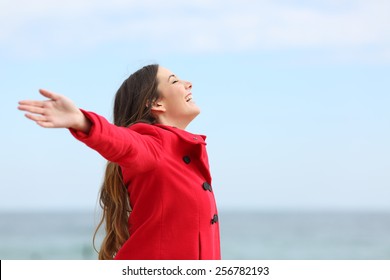 Happy fashion woman profile breathing deep fresh air in winter on the beach