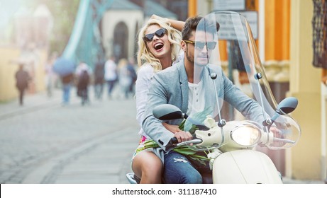 Happy Fashionable Couple Riding On Scooter