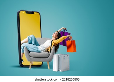 Happy fashionable young woman sitting and holding shopping bags in a smartphone, she is doing online shopping, blank copy space - Shutterstock ID 2218256805