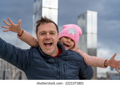 Happy Father Carrying Piggyback Ride To His Daughter Outdoors. Cheerful Girl Piggyback Riding Dad In Park, Spending Time Together