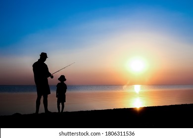 Fröhliche Vater- und Kinderfischer fangen Fische am Meer auf Natursilhouette Reisen