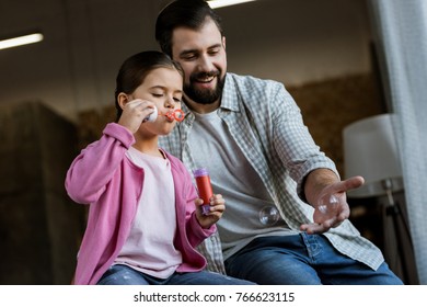 Happy Father With Daughter Blowing Bubbles At Home