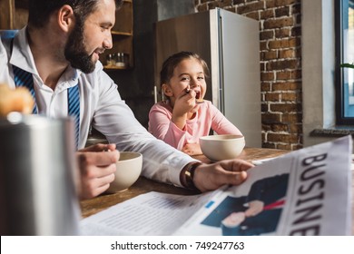 happy father and daughter eating breakfast together while they preparing for work and school - Powered by Shutterstock