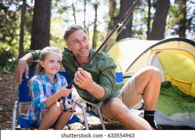 Happy father and daughter fishing at campsite in forest - Powered by Shutterstock