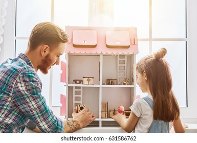 Happy Father And Daughter Girl Play With Doll House At Home. Funny Lovely Family Is Having Fun In Kids Room.