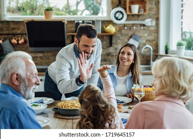 Happy father and daughter giving high-five to each other during a family lunch in dining room. - Powered by Shutterstock