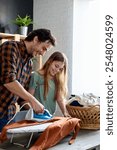 Happy father with daughter at home doing household chores and ironing together.