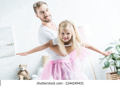 Happy Father And Daughter In Pink Tutu Skirts Dancing At Home 