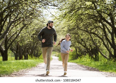 happy father and daughter running on path in park
