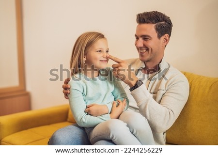 Happy father and daughter spending time together and having fun at their home.